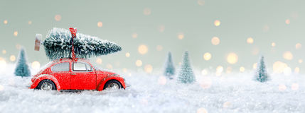 red-car-carrying-christmas-tree-snowy-forest-77615139